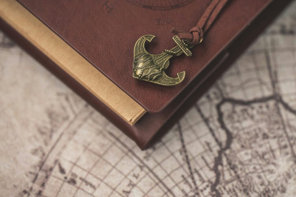 A vintage-themed notebook with an anchor ornament resting on an old map, evoking exploration and adventure.